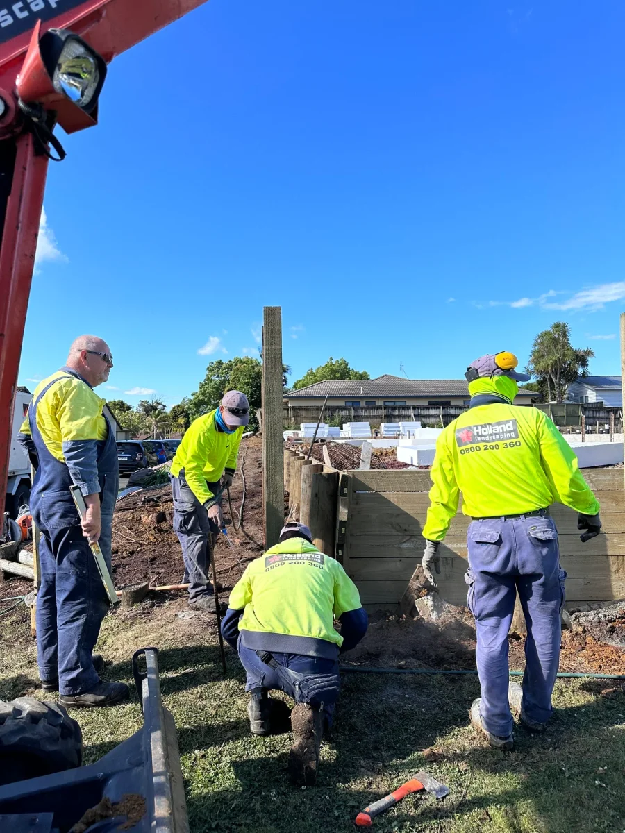 Holland Landscaping crew building a retaining wall at a commercial Auckland site